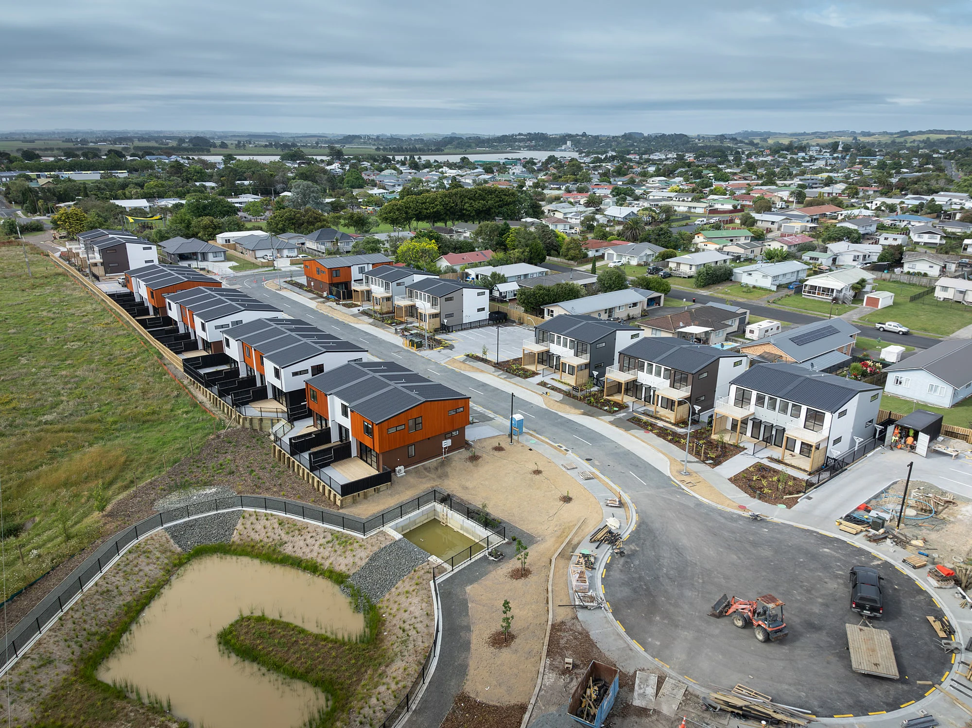 An aerial of the completed Dargaville terrace development, two runs of orange, white and dark clad homes along a new street