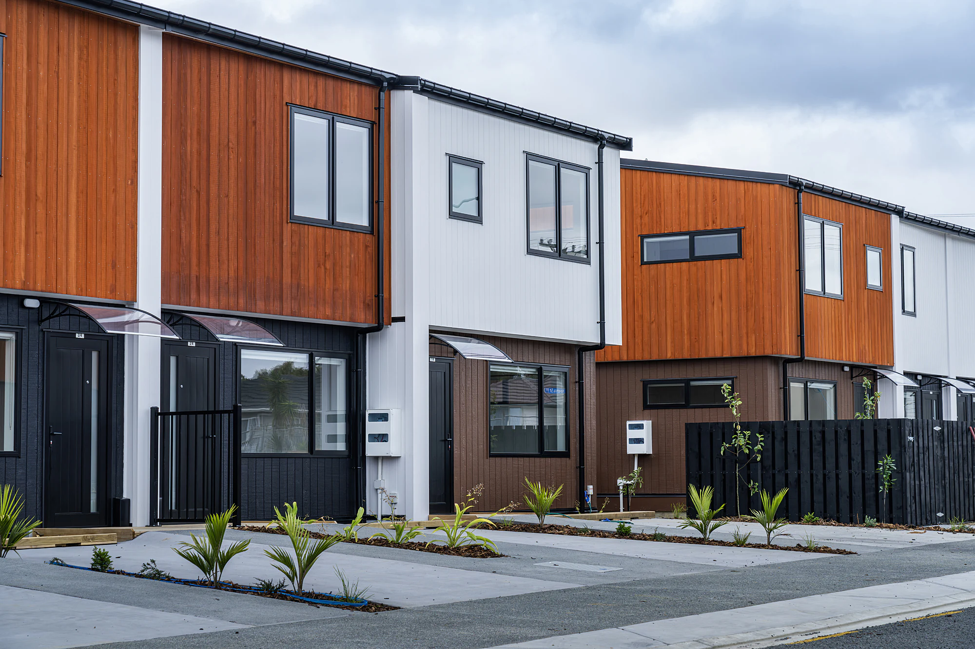 A close, angled view of the terrace row's two-storey facade, orange timber cladding beside white panel